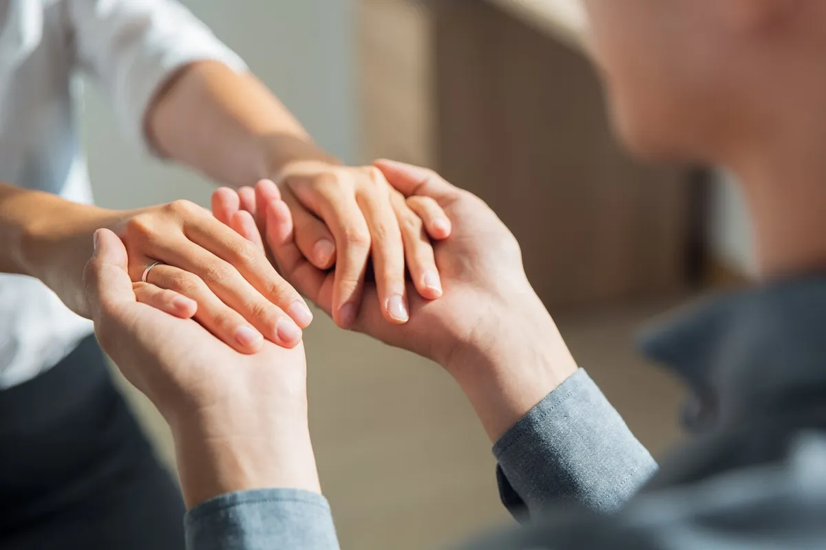 Two people holding hands, symbolizing supportive care between a professional and an individual