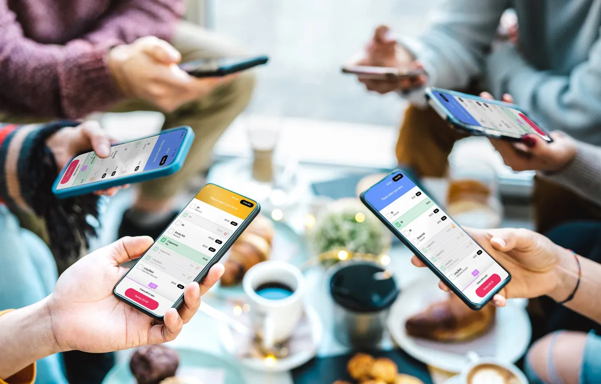 Group of friends viewing the HungryHungry ordering app on their phones at a cafe table